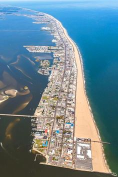 an aerial view of the beach and ocean in this city, with sand dunes on both sides