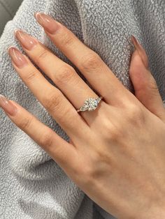 a woman's hand with a diamond ring on her left hand, and a towel in the background