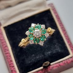 A traditional, vintage cluster ring featuring round emeralds and round, brilliant-cut diamonds, claw set in a floral cluster, mounted in 18ct yellow gold with elegant rope detailing to the shoulders. A beautiful ring that looks stunning on the finger. Circa 1970-1980. Unmarked, tested as 18ct gold. The cluster measures approximately 12.3mm x 10.6mm. The approximate weight is 4.0 grams. Please note that the antique ring box pictured is for display purposes only. Thank you. Ring size S (UK) or 9 1/8 (US) - this ring can be adjusted in size in our workshop. Please get in touch to discuss sizing options and lead time. For UK to US ring size conversions we use www.ringsizes.co as our reference chart. CONDITION: In very good vintage condition, with some light surface wear commensurate with age. Vintage Cluster Ring, Antique Ring Box, Cluster Rings, Cluster Engagement Ring, Antique Ring, Sterling Silver Brooch, Silver Brooch, Diamond Cluster Ring, Multi Stone Ring