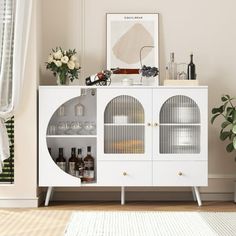 a white cabinet with glass doors and shelves in a living room next to a potted plant