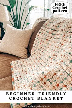 a crocheted blanket sitting on top of a couch next to a potted plant