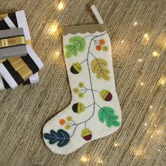 a decorated christmas stocking sitting on top of a floor next to a present box