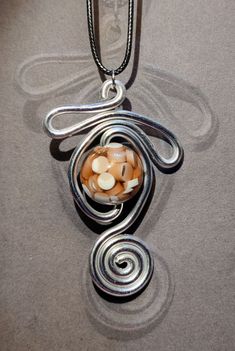 a silver necklace with an orange and white bead hanging from it's center