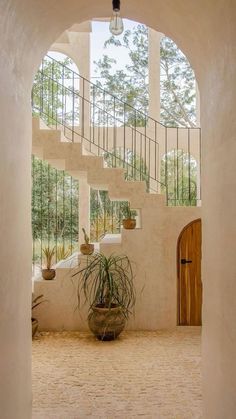 an archway leading to the upper level of a house with potted plants on either side