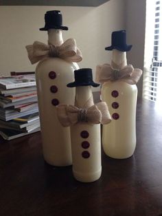 three wine bottles decorated like snowmen with hats and bow ties on them sitting on a table