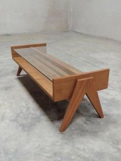 a coffee table with a glass top and wooden legs on concrete floor in an empty room