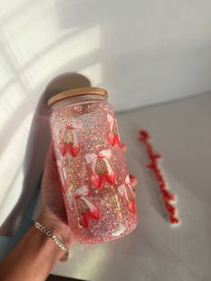 a hand holding a jar with strawberries on it next to candy canes and candies