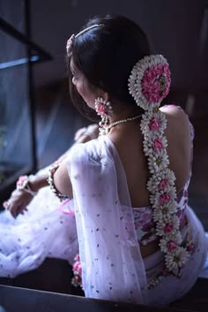 a woman sitting on the ground with flowers in her hair and wearing a white dress