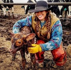 a woman kneeling down next to a baby cow