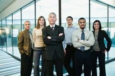 a group of business people standing in front of a glass wall with their arms crossed