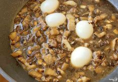 some kind of food in a pan on a stove top with eggs and meats