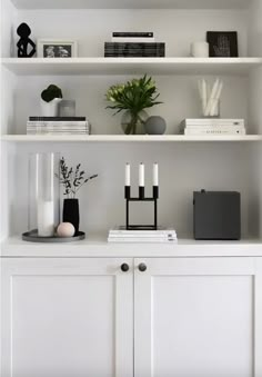 a white shelf filled with books and candles