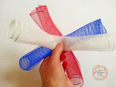 a hand is holding three pieces of white, red and blue mesh with the end rolled up