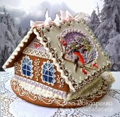 a decorated gingerbread house on a doily with snow covered trees in the background