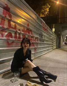 a woman sitting on the ground with her legs crossed and wearing knee high black boots