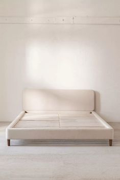 a white bed sitting in the middle of a room next to a wall and floor