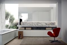 a modern bathroom with marble counter tops and white cabinets, along with a red chair