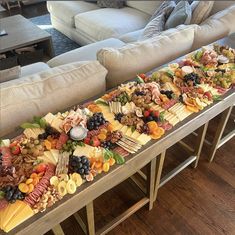 a long table filled with lots of different types of cheeses and fruit on top of it