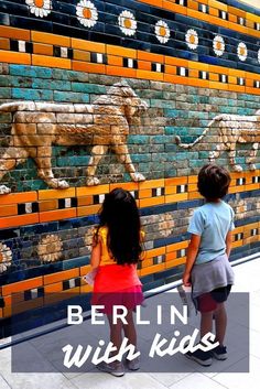 two children looking at a wall with lions on it and the words berlin with kids