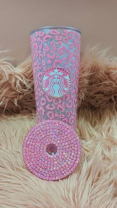 a pink and silver starbucks cup sitting on top of a furry rug