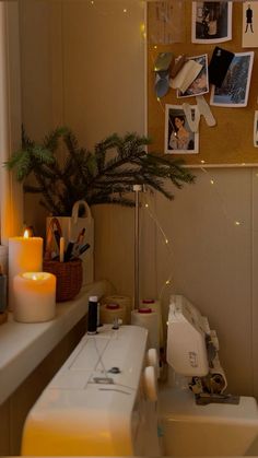 a bathroom with candles and pictures on the wall next to a sink in front of a window