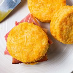 three pastries sitting on top of a white plate next to a knife and fork