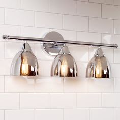 three light bathroom fixture with white tiles in the backgrounnd and silver fixtures