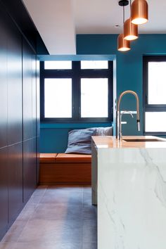 a kitchen with blue walls and marble counter tops, along with an island in the middle