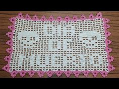 a pink and white crocheted doily on a wooden table