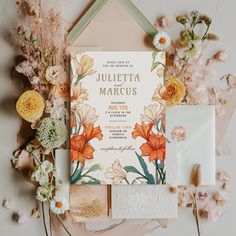 the wedding stationery is laid out on top of flowers and other things to include