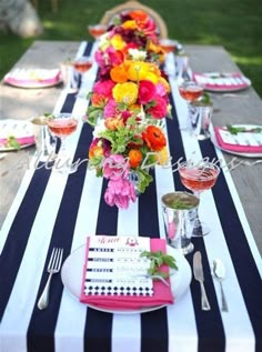 a long table with black and white striped runneres topped with colorful flowers in vases