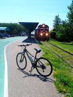 a bike parked next to a train on the tracks in front of a railroad track