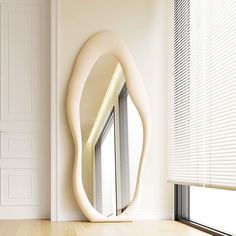 a mirror sitting on top of a wooden floor next to a window covered in blinds