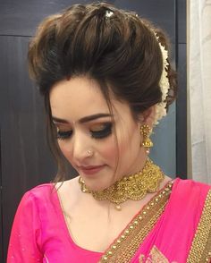 a woman in a pink sari with gold jewelry on her neck and headpiece