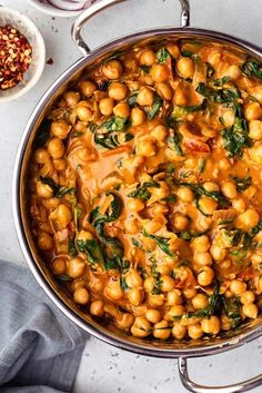 a pot filled with chickpeas and spinach on top of a white table