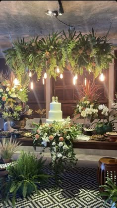 a wedding cake is surrounded by greenery and potted plants