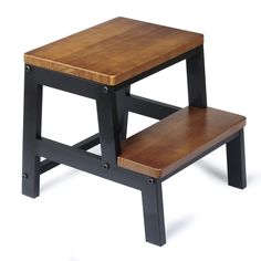 a small wooden step stool sitting on top of a white floor next to a table