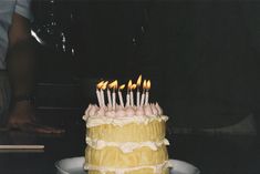 a yellow cake with white frosting and lit candles