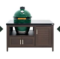 a big green egg sitting on top of a wooden table next to a cabinet with drawers