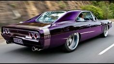 a purple muscle car driving down the road