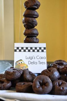 chocolate donuts stacked on top of each other in front of a sign that says luigi's caso delia tires