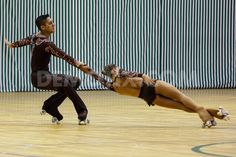 two people on roller skates in an indoor court with one falling to the ground