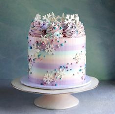 a multi - layer cake with frosting and flowers is on a stand against a blue background