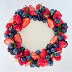 a cake with berries and blueberries arranged in the shape of a wreath on top