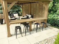 an outdoor bar with stools and tables in the middle of a patio area surrounded by greenery