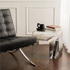 a black chair sitting next to a table with a book on it and a coffee cup