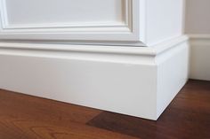 the corner of a white frame on top of a wooden floor