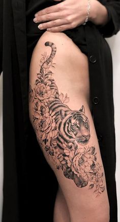 a woman's thigh with a tiger and flowers tattoo on the side of her leg