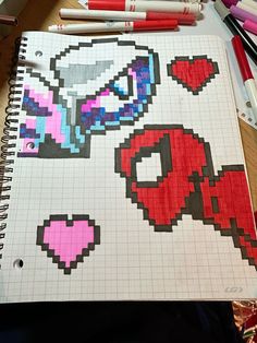 a notebook with some pixel art on it and crayon markers next to it