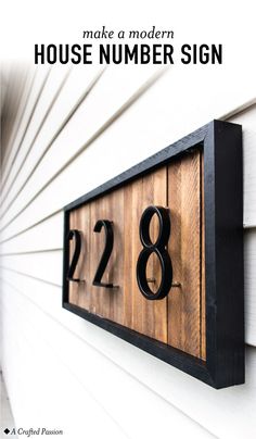 a wooden house number sign mounted to the side of a white building with black numbers on it